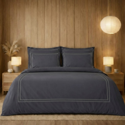 Dark blue bedding set on a bed in a bedroom with wooden walls and lamps.