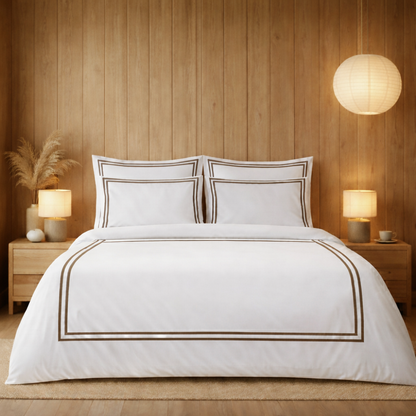 Bedroom with wooden walls, white bedding with brown trim, and two lamps on nightstands.