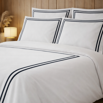 White bedding set with black piping on a bed in a bedroom setting.