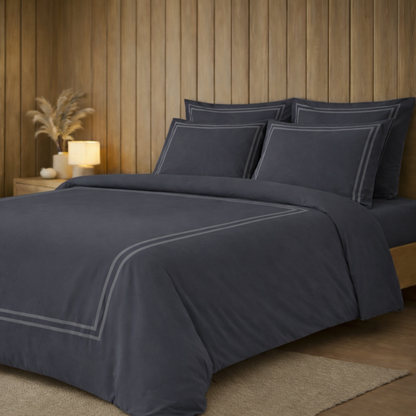 Navy blue bedding set with white piping on a bed in a bedroom setting.