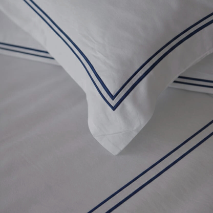 White pillows with blue trim on a matching fabric background